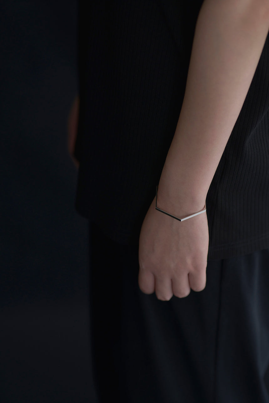 6角形(Hexagon)の形をしたシンプルな、真鍮製アクセサリーのバングルをつけた女性モデル