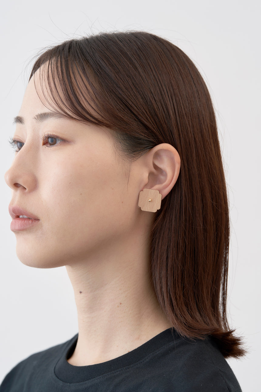 木瓜紋をモチーフにした18Kイエローゴールドの木製ピアスとモデル。