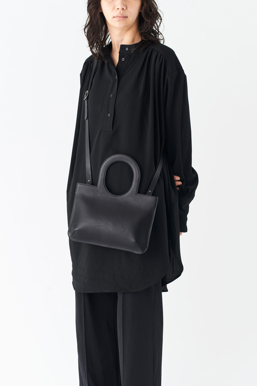 ミニマルなレザーのショルダーハンドバッグを掛けるモードな女性モデル