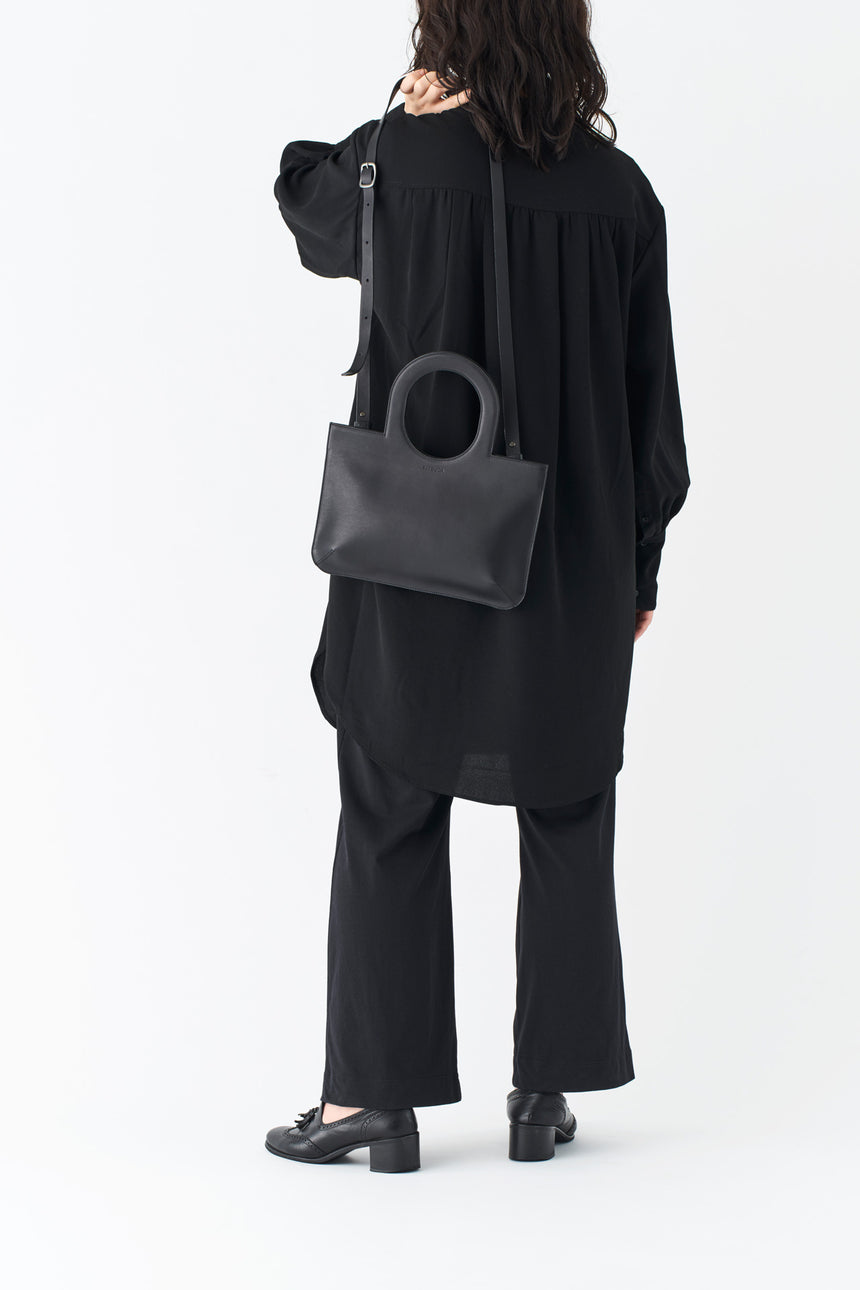 ミニマルなレザーのショルダーハンドバッグを掛けるモードな女性モデル