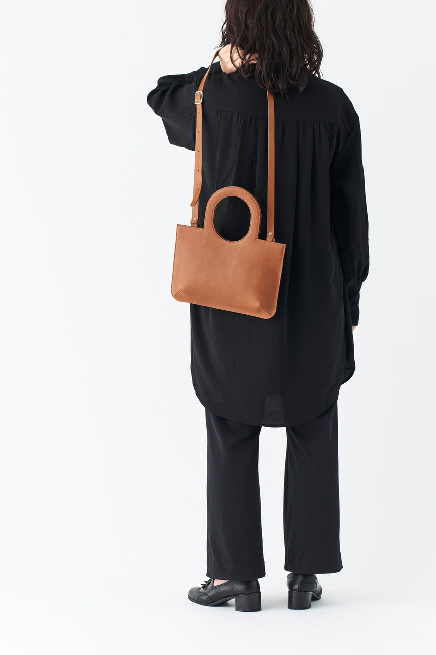 ミニマルなレザーのショルダーハンドバッグを持つモードな女性モデル