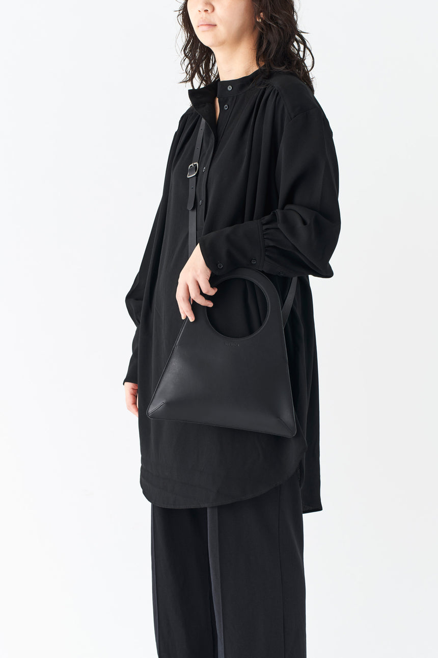 シンプルなレザーのショルダーハンドバッグを掛けるモードな女性モデル