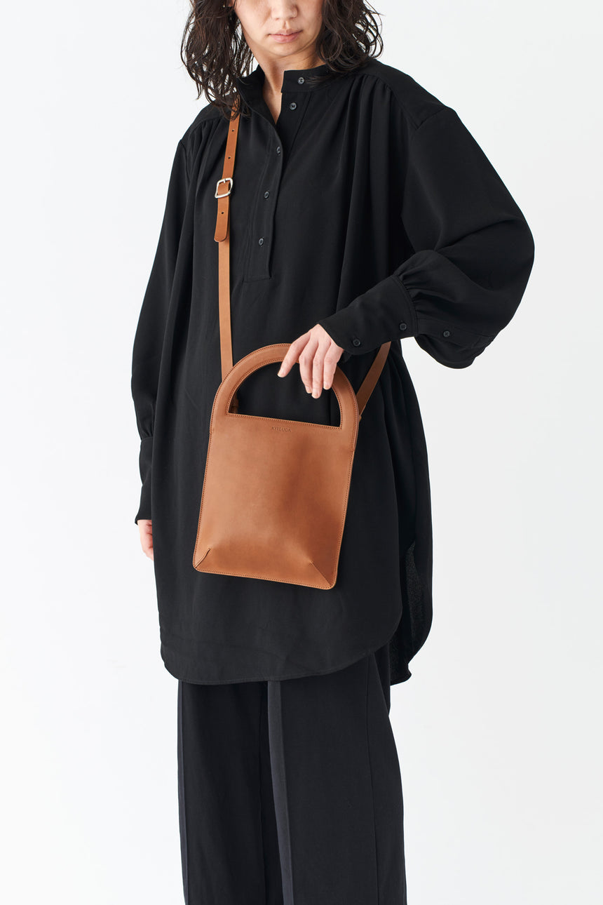 ミニマルなレザーのショルダーハンドバッグを持つモードな女性モデル